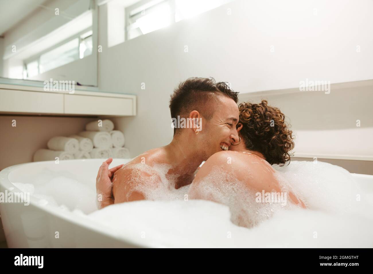 Schönes queeres Paar, das zusammen ein romantisches Schaumbad genießt. Glückliches junges Paar, das sich in der Badewanne amüsieren kann. Junge LGBTQ+ Paare, die Qual ausgeben Stockfoto