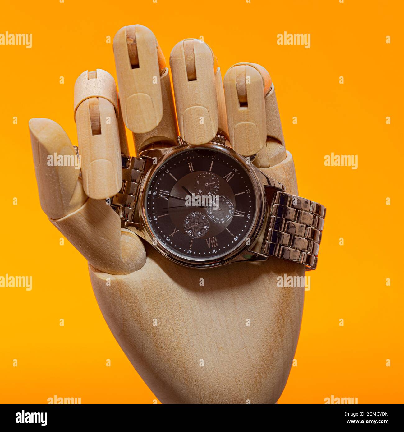 Holzzeiger mit modischer Chronographenuhr auf orangefarbenem Hintergrund Stockfoto
