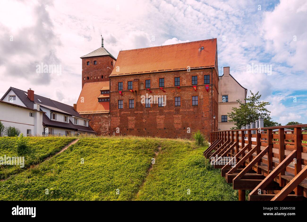 Blick auf die gotische Burg der pommerschen Herzöge in Darłowo. Ein Graben und eine Brücke im Vordergrund. Die Mauern der Burg sind aus rotem Backstein und die Stockfoto