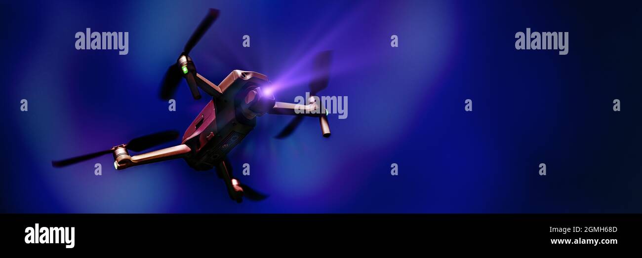 Fliegende Drohne mit Kamera auf dunkelblauem Hintergrund mit Kopierraum. Luftgetragener Quadcopter. Auch bekannt als Drohne oder UAV, unbemanntes Luftfahrzeug. Niedriger Angl Stockfoto