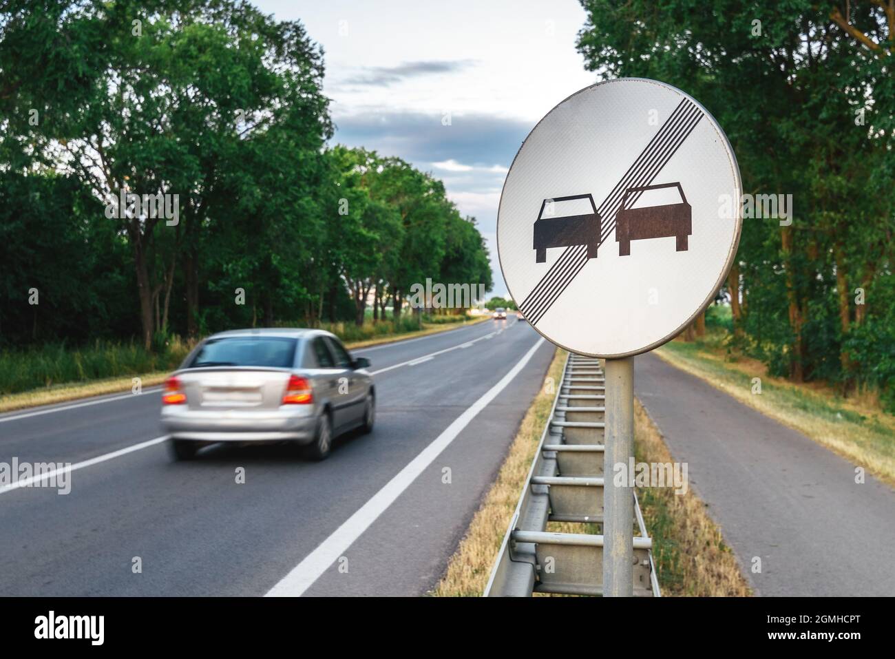 Ende der Straße ohne Überholmanzeichen und Auto in Bewegung, das den Highway hinunterfährt Stockfoto