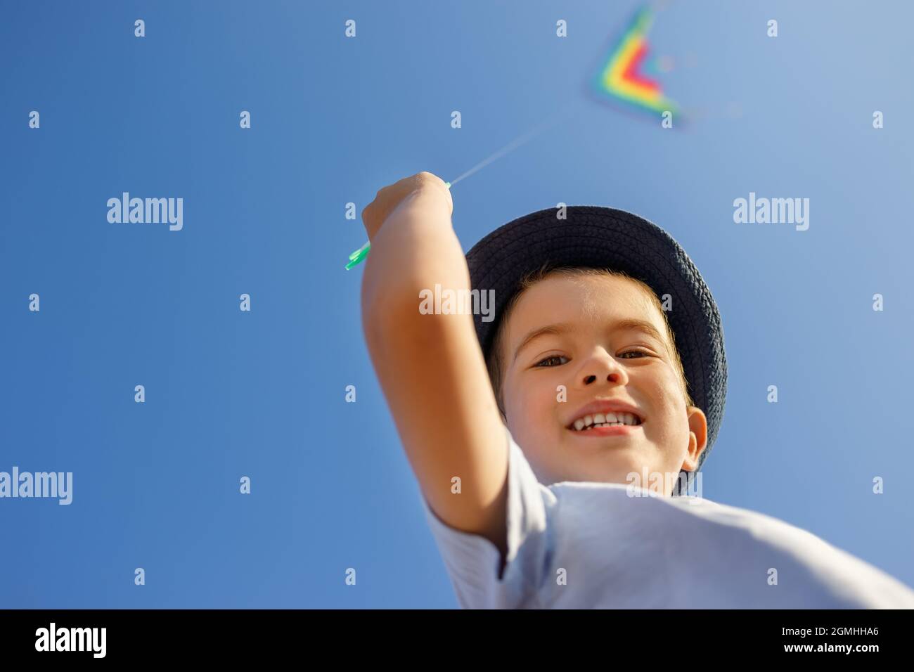 Porträt eines lächelnden kleinen Jungen mit fliegenden bunten Drachen Stockfoto