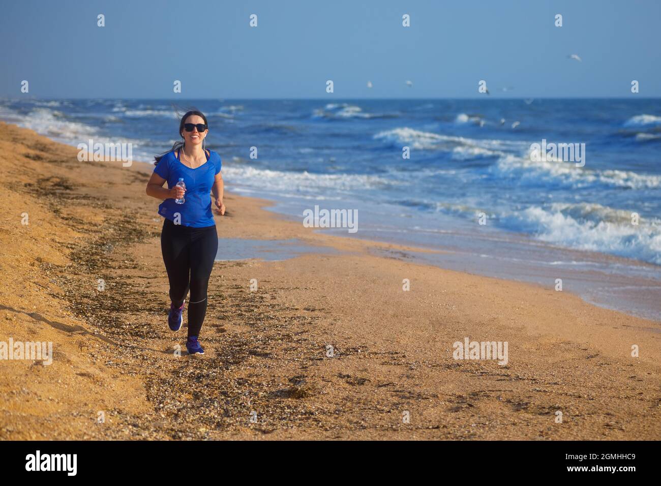 Frau, die am Strand am Meer läuft und Musik hört Stockfoto