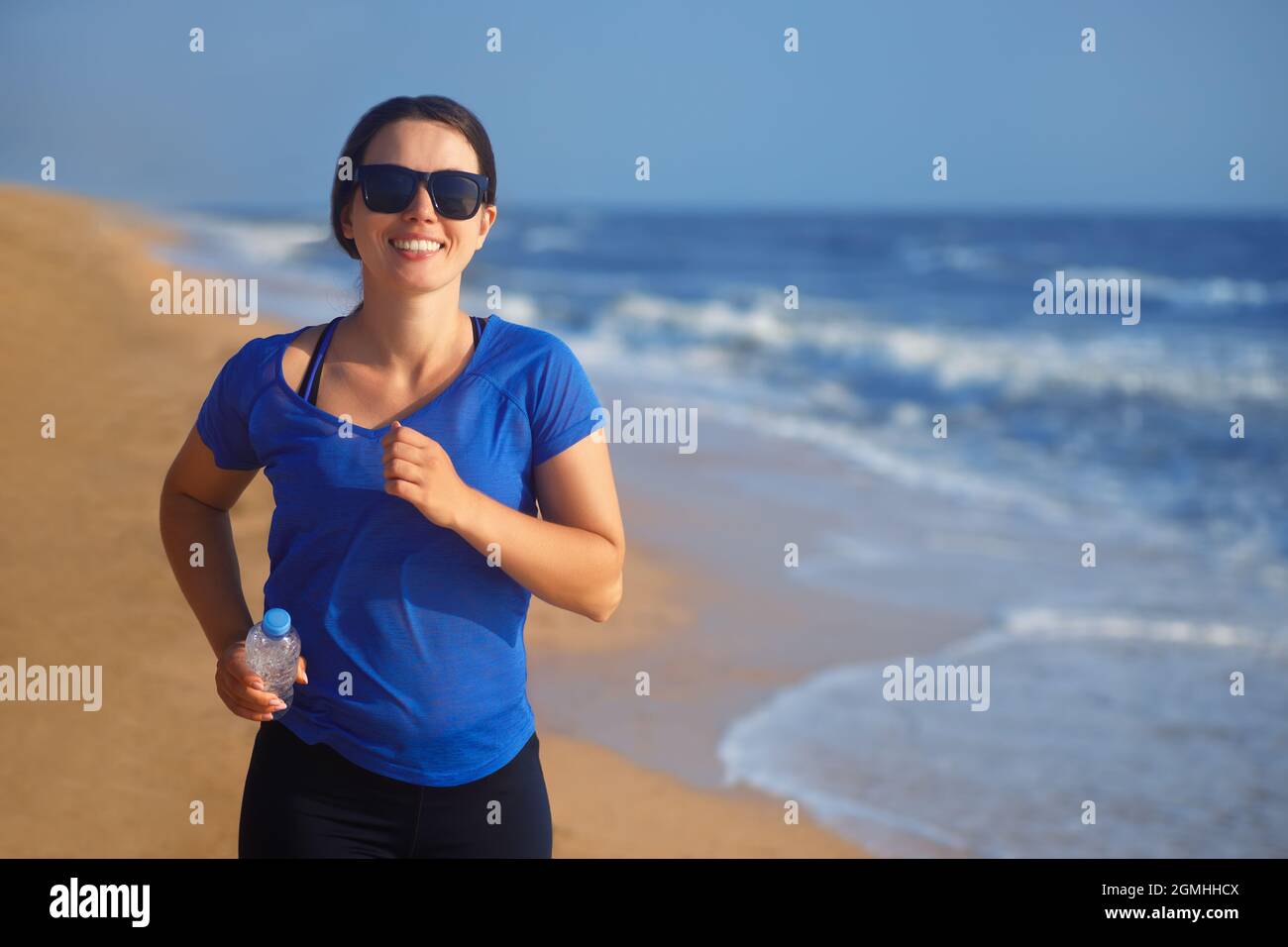 Porträt einer glücklichen Frau, die am Strand läuft Stockfoto