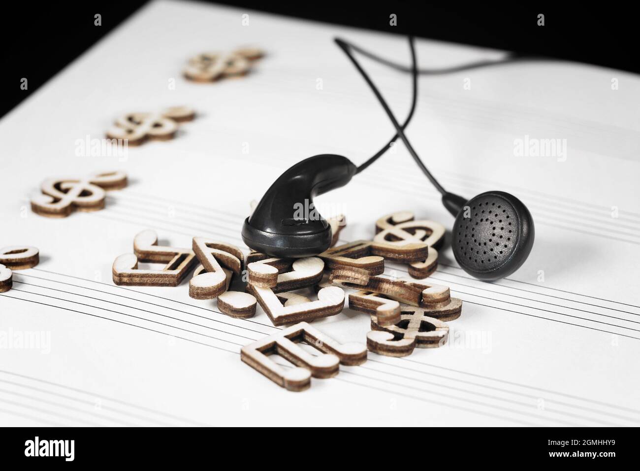 Mit schwarzen Kopfhörern häufen sich hölzerne Musiknoten. Stockfoto