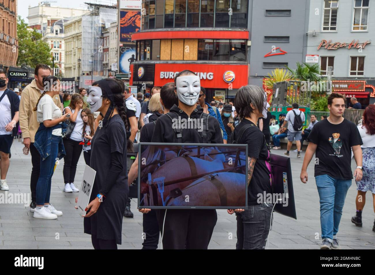 London, Großbritannien. September 2021. Aktivisten, die Guy Fawkes Masken tragen, stehen mit Bildschirmen, auf denen grafische Videos von Tieren gezeigt werden, die während der veganen Kampagne auf dem Leicester Square für Lebensmittel getötet wurden. Die Passanten werden ermutigt, vegan zu sein, indem grafische Aufnahmen der Schrecken gezeigt werden, die Tiere in Schlachthöfen, in der Tierzucht und in der Fischwirtschaft durchmachen. Kredit: SOPA Images Limited/Alamy Live Nachrichten Stockfoto