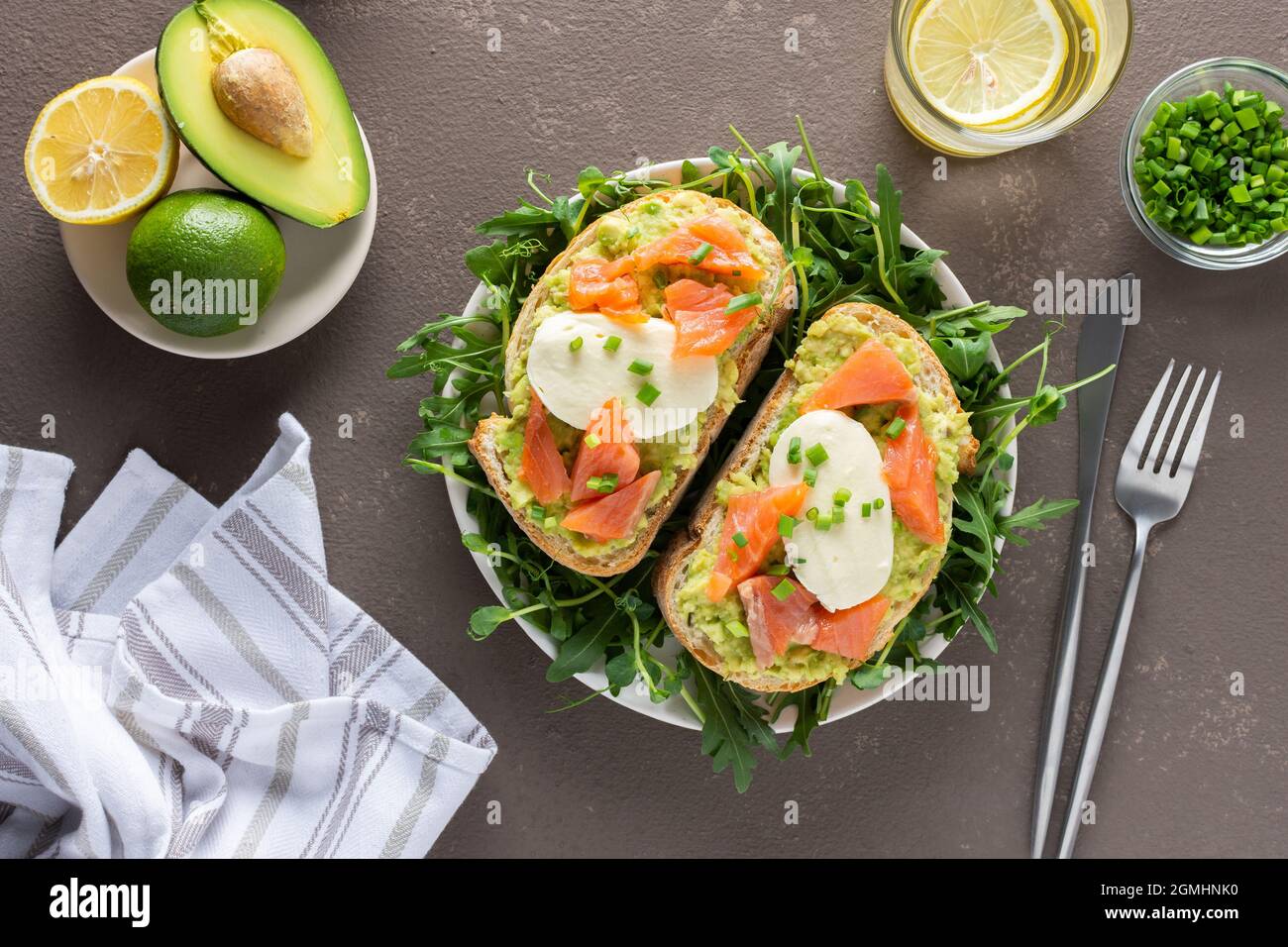 Leckeres herzhaftes Frühstück, Sandwiches mit Avocado-Paste, Lachs und Mozzarella auf einem Teller mit Rucola und Erbsensprossen Stockfoto