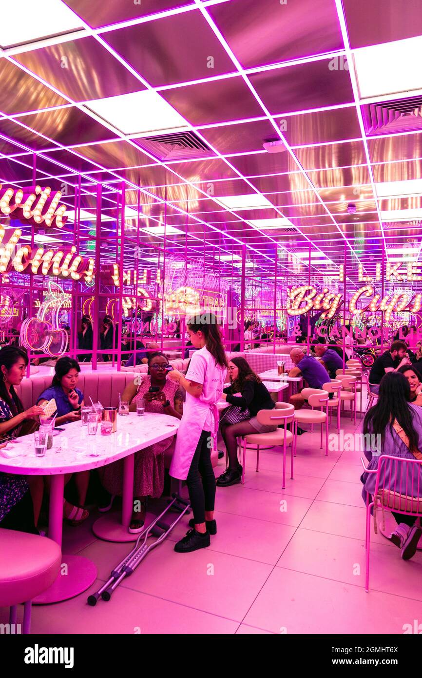 Im El&N Soho Café, London, Großbritannien, befindet sich ein in Retro verspiegeltes, pinkfarbenes Interieur mit Markelampen Stockfoto