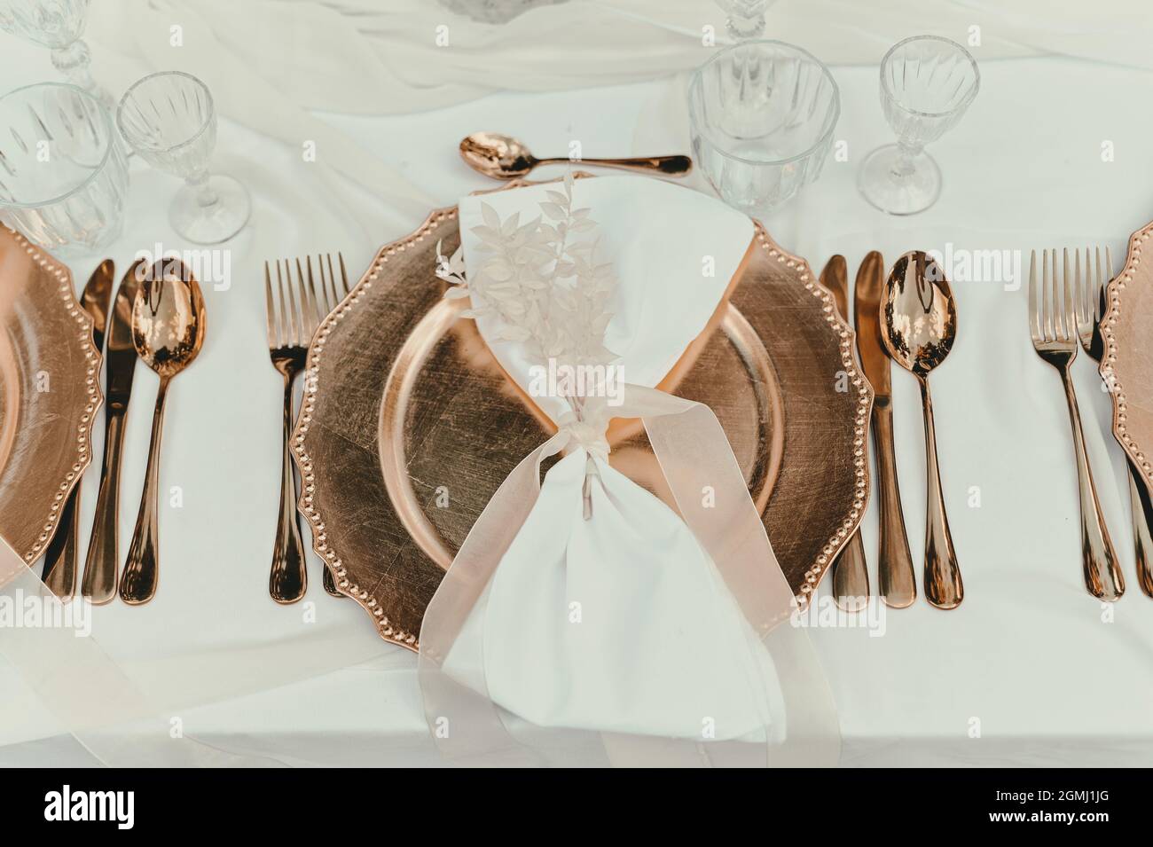 Wunderschöne goldene Teller auf dem Tisch am Hochzeitstag. Dekoration für Feiern, Hochzeiten und Geburtstage Stockfoto