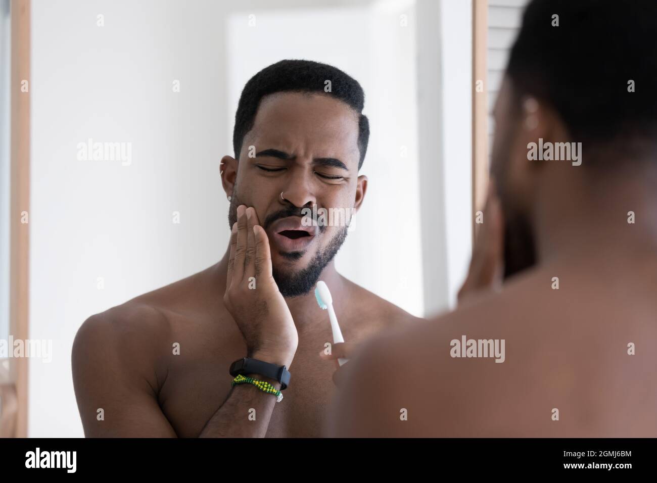 Ein hübscher afrikanischer Mann spürt Schmerzen beim Zähneputzen Stockfoto