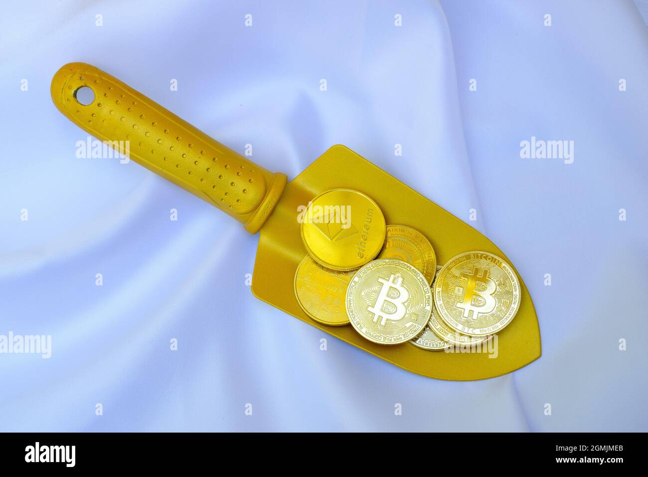 Goldene Bitcoin-Münzen auf einer goldenen Schaufel auf weißem Hintergrund Stockfoto
