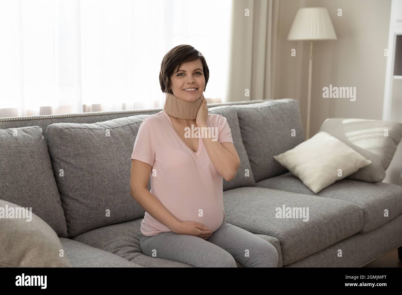 Frau mit fortgeschrittener Schwangerschaft sitzen auf dem Sofa im medizinischen Kragen Stockfoto