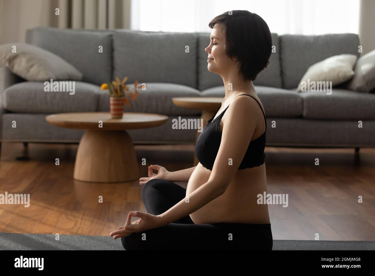 Zukünftige Mutter erwartet Kind tun einfache Meditation im Wohnzimmer Stockfoto