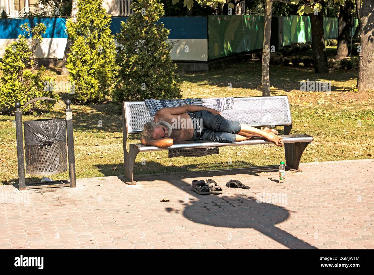 Dnepropetrovsk, UKRAINE - 09.13.2021: Ein obdachloser Bettler schläft auf einer Parkbank. Soziale Probleme. Bettler - Arbeitslose, Flüchtlinge, Auswanderer. Stockfoto