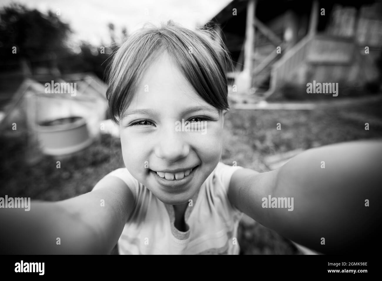 Ein kleines Mädchen macht ein Selfie im Dorf. Schwarzweiß-Foto. Stockfoto