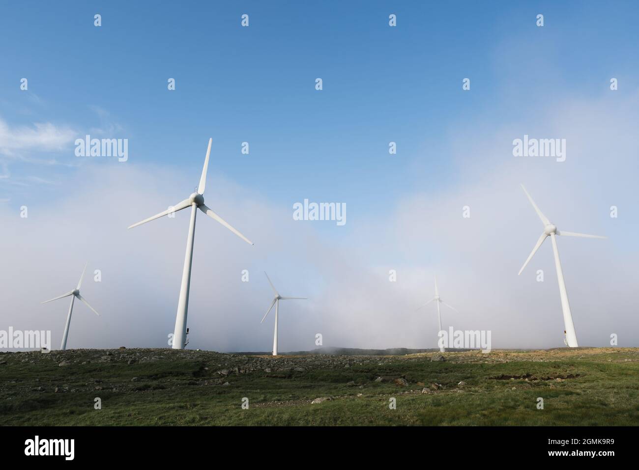 Grüne Energie in Form von Windparks auf einem Hügel in den Wolken Stockfoto