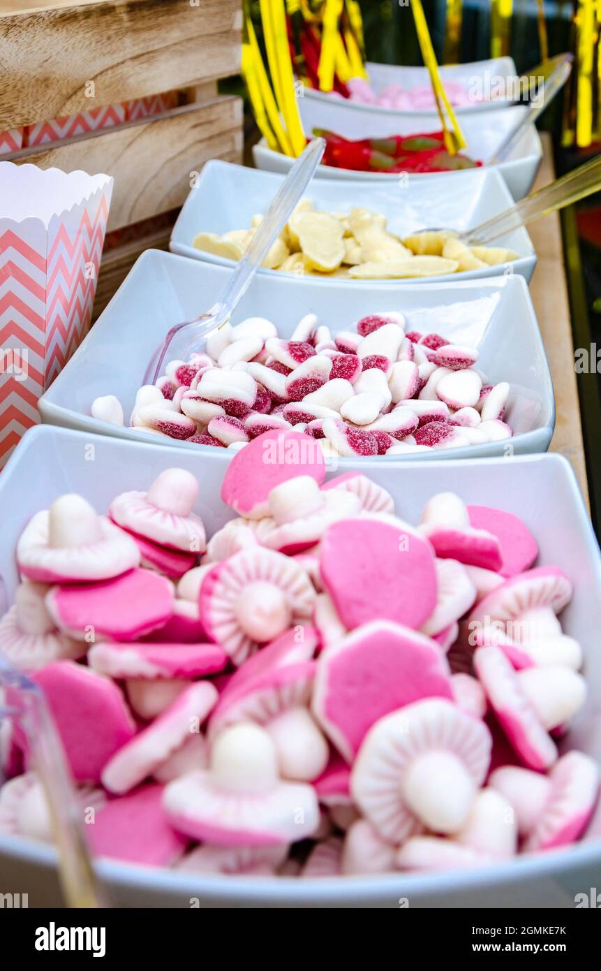Schüsseln aus rosa, weißen und roten Süßigkeiten bilden ein Pic n Mix für Leute, die sich auf einer Party selbst helfen können. Stockfoto