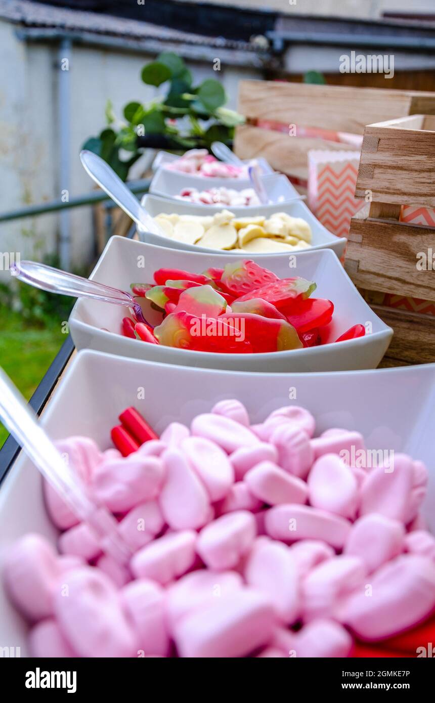 Schüsseln aus rosa, weißen und roten Süßigkeiten bilden ein Pic n Mix für Leute, die sich auf einer Party selbst helfen können. Stockfoto