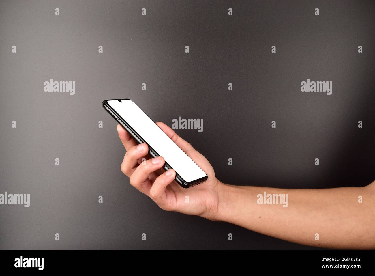 Handhalterahmen weniger Handy mit weißem Bildschirm für Nachrichten oder Anzeigen auf dunklem Hintergrund, leerer Bildschirm Smartphone in der Hand des Mannes Stockfoto