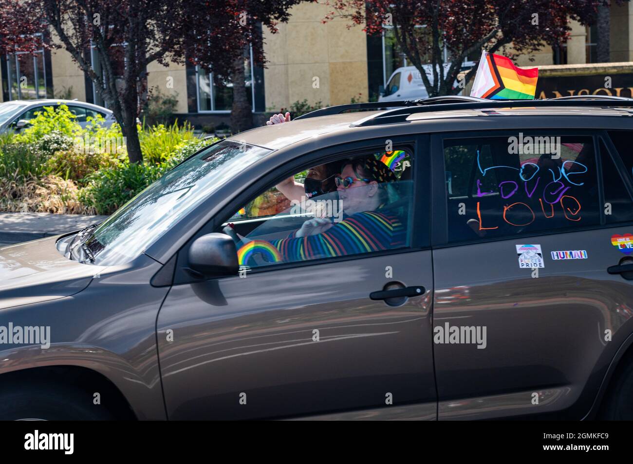 Die Teilnehmer winken aus einem Auto mit einem Spruchband mit den Aufsagen „Liebe ist Liebe“, „Schwarze Leben“ und mehr nehmen an einer Veranstaltung der Placer County Pride-Karawane Teil Stockfoto