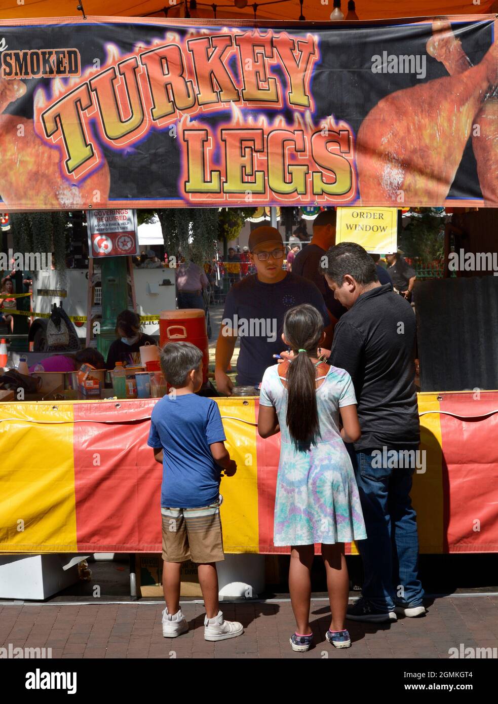 Kunden kaufen geräucherte putenbeine bei einem Lebensmittelhändler auf der jährlichen Fiesta de Santa Fe in Santa Fe, New Mexico. Stockfoto