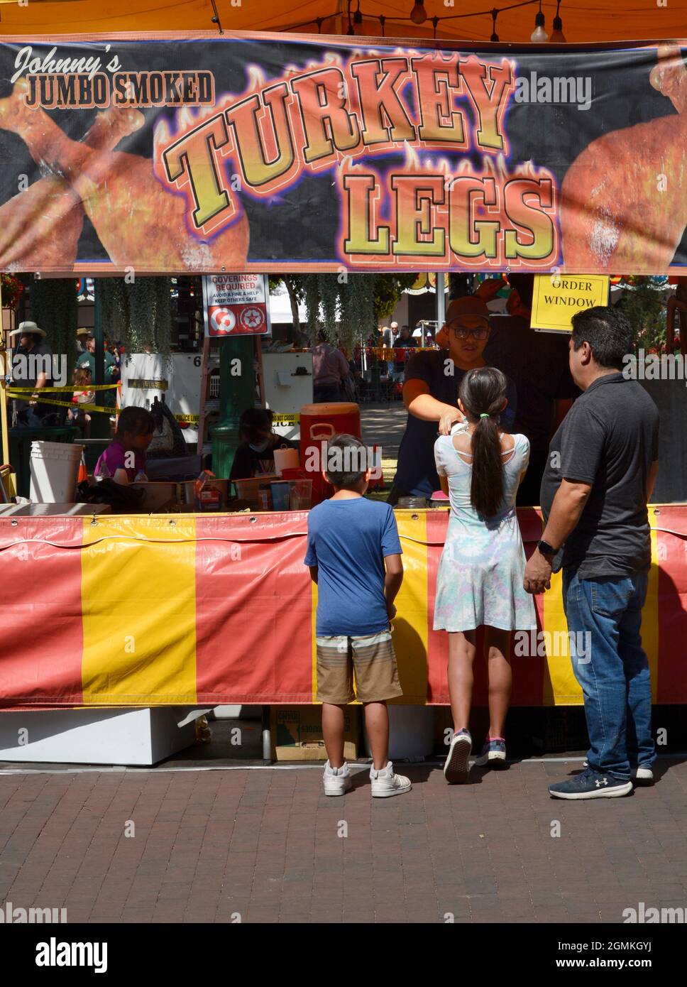 Kunden kaufen geräucherte putenbeine bei einem Lebensmittelhändler auf der jährlichen Fiesta de Santa Fe in Santa Fe, New Mexico. Stockfoto