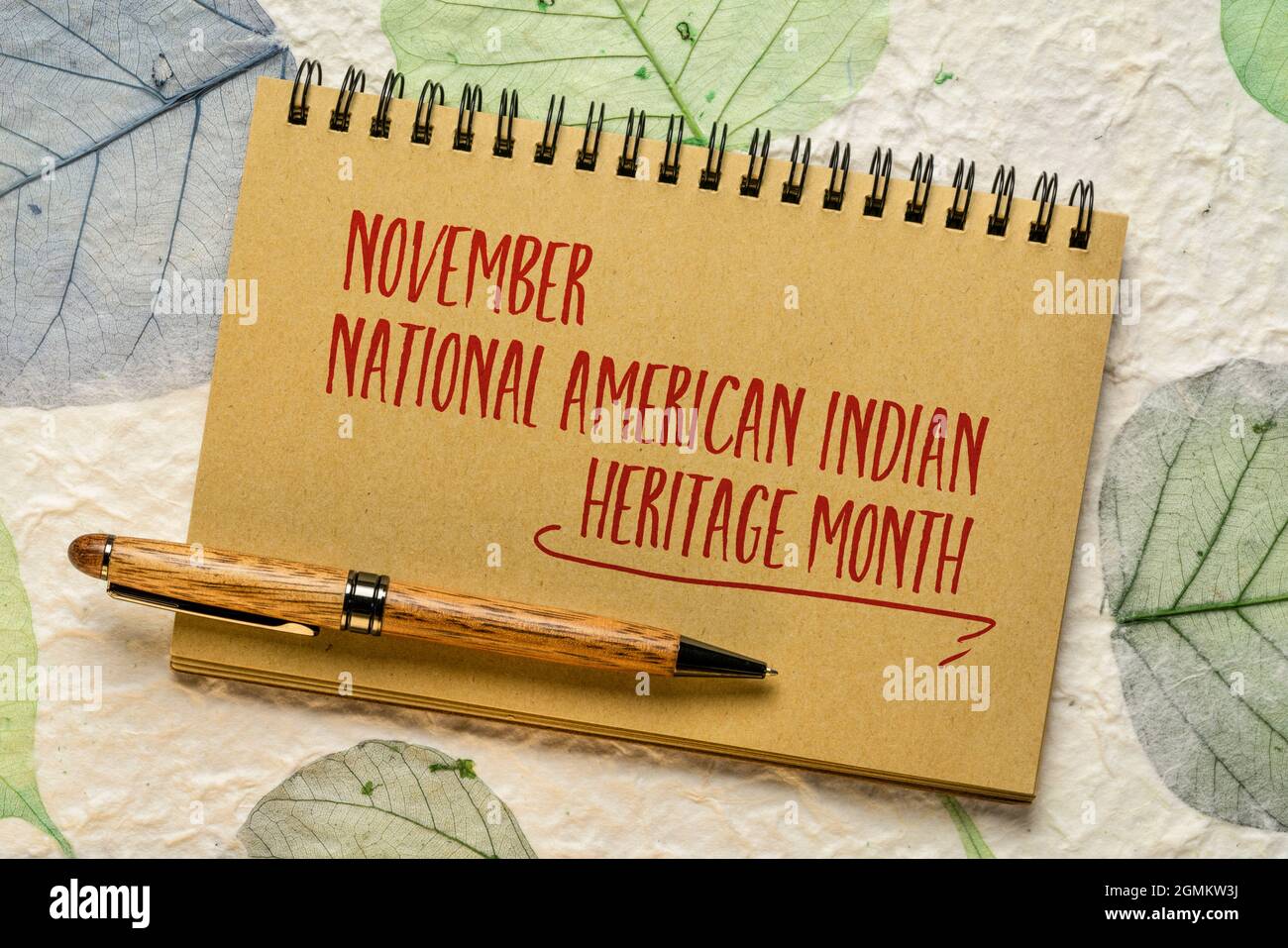 November - National American Indian Heritage Month, Handwiting in einem Spiralheft gegen handgemachtes Papier mit Blatteinschlüssen, Erinnerung an Historica Stockfoto