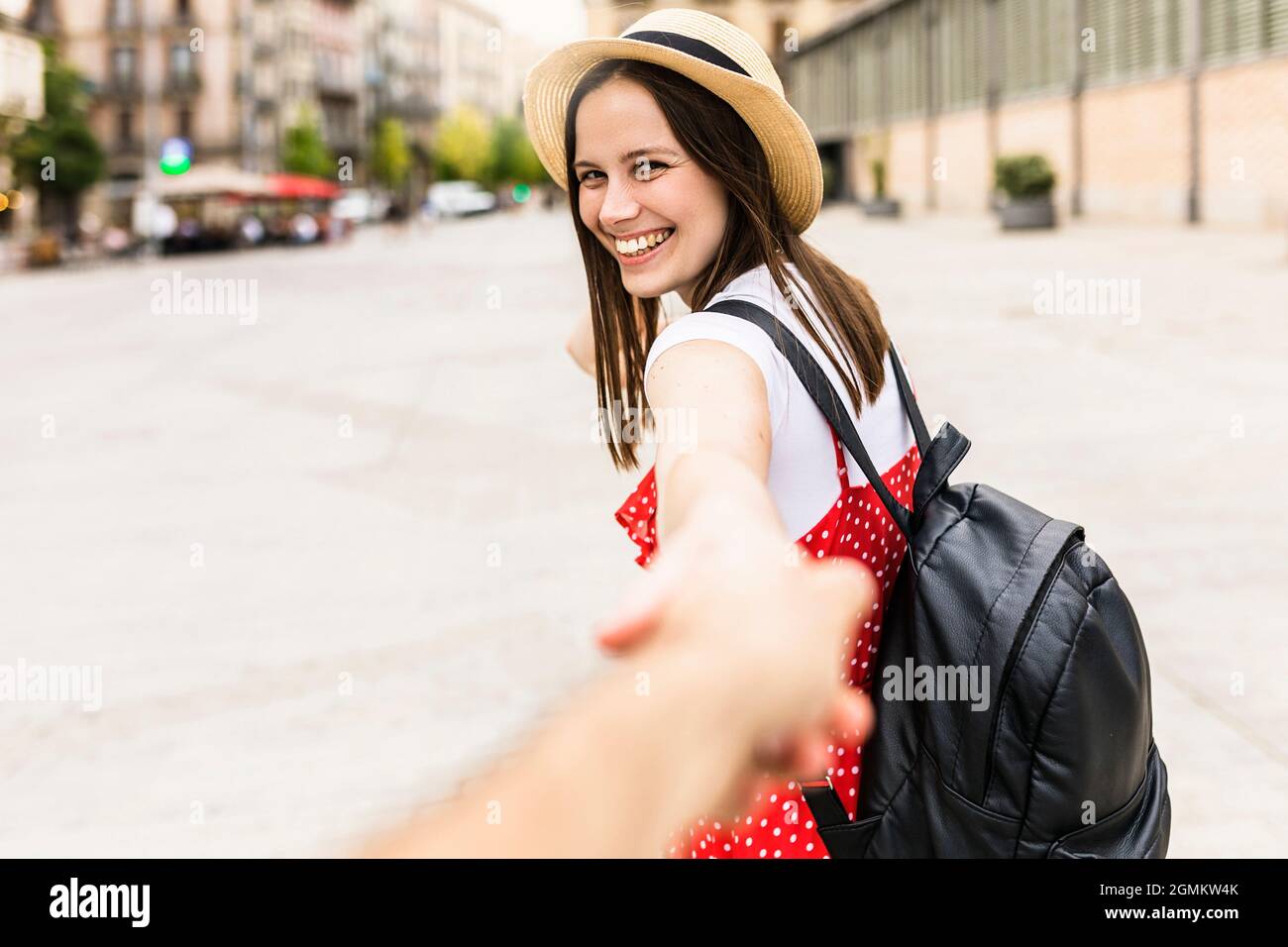 Fröhliche trendige Frau hält Freund Hand in der Stadt Stockfoto