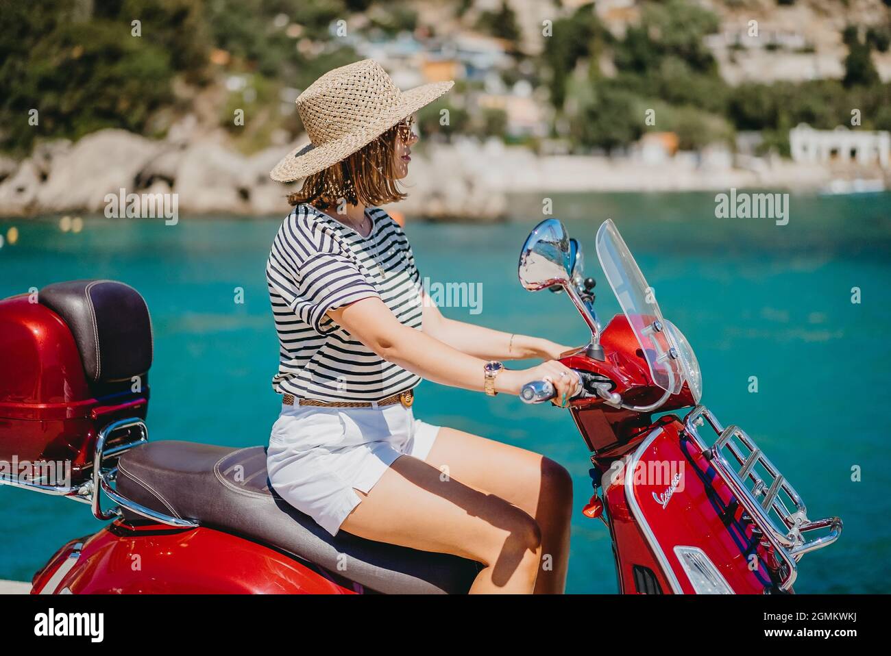 Korfu, Griechenland - September, 2021. Frau sitzt auf Vespa Roller Motorrad  in Süßigkeiten apfelrot Farbe, Pier in Paleokastritsa Dorf, Luxus-Resort  Stockfotografie - Alamy