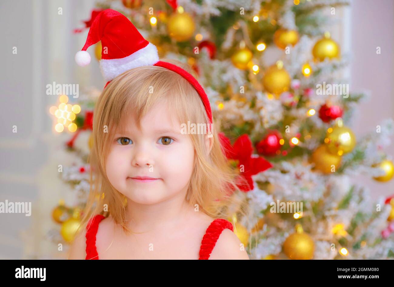 Mädchen mit einem Hut des Weihnachtsmanns steht in Neujahrsdekorationen Stockfoto