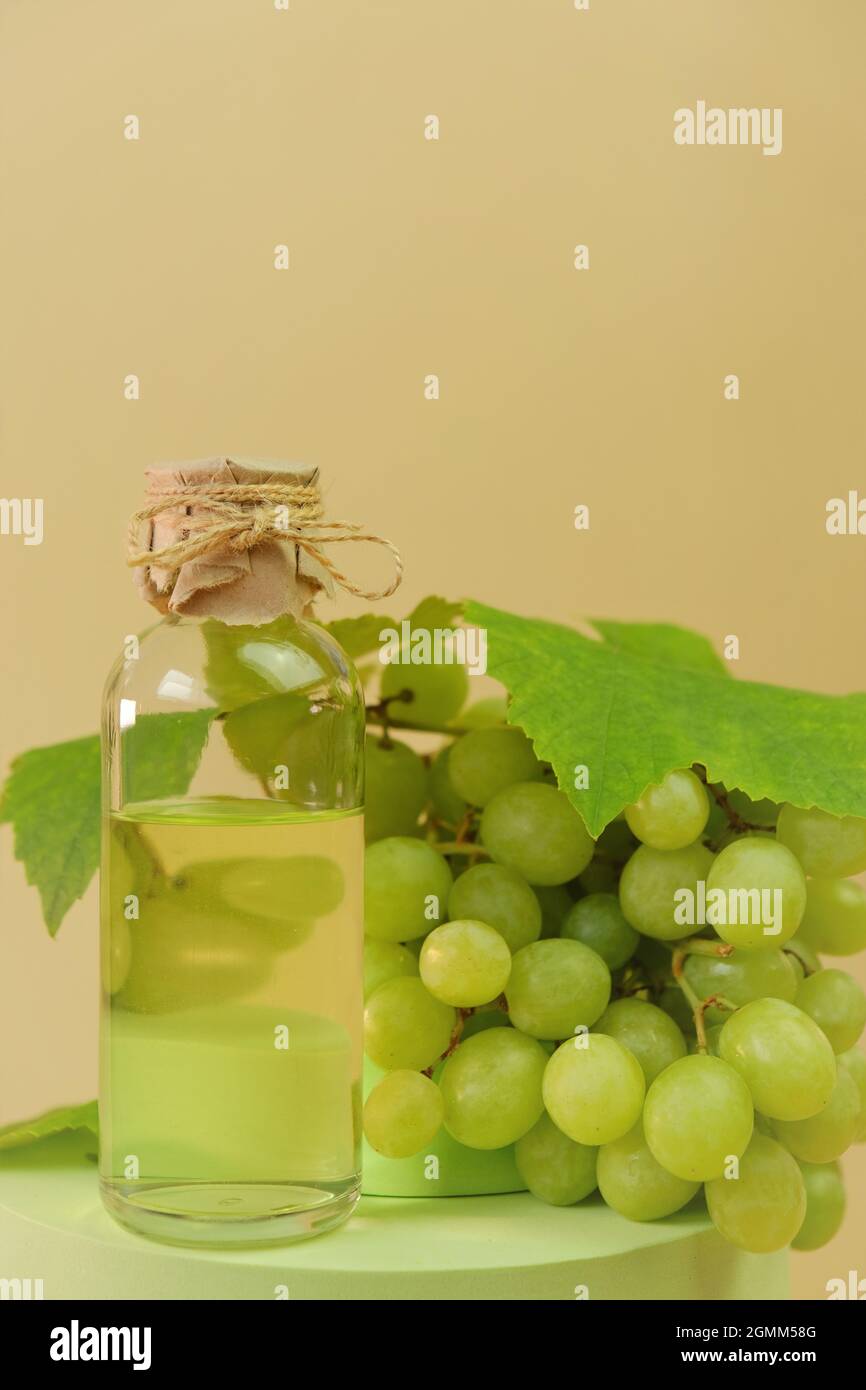 Traubenkernöl-Flasche auf dem Podium auf beigefarbenem Hintergrund. Bio Natürliches Bio Traubenkernöl. Stockfoto