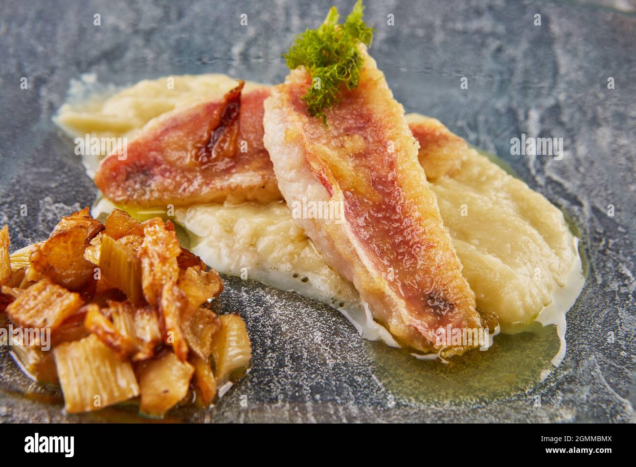 Barbunya-Fischstücke mit Fenchel und Sauce auf Glasplatte. Stockfoto