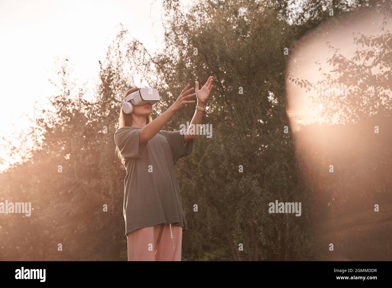 Ein Mädchen mit einer Virtual-Reality-Brille. Er reicht seine Hände an den Sonnenstrahl. Hochwertige Fotos Stockfoto