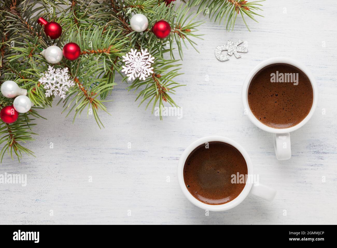 Zwei Tassen Kaffee und Fichtenzweig mit Weihnachtsdekorationen auf altem schäbigen Holzhintergrund. Stockfoto