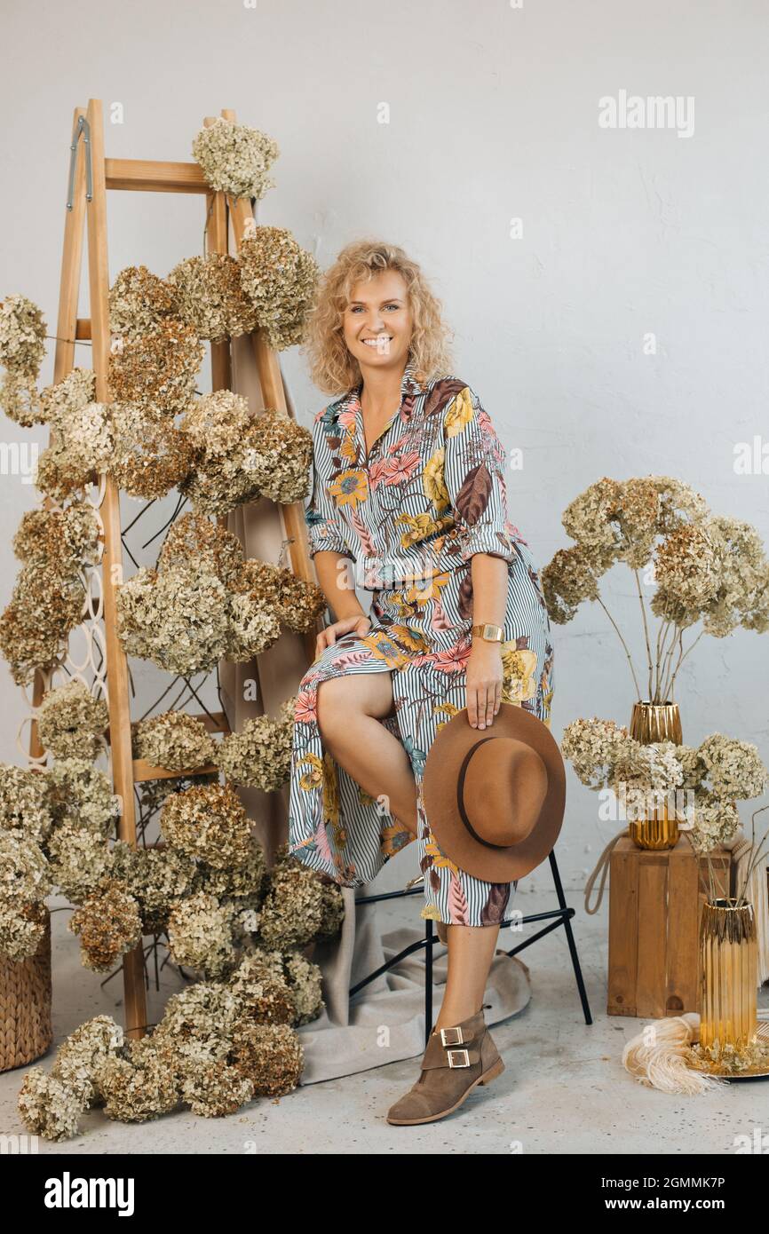 Schöne Blumenarrangements mit schönen getrockneten Hortensien Blumen, in stilvollem Raum, auf Holztreppe. Unter ihnen ist glückliche Frau Floristin in Stockfoto
