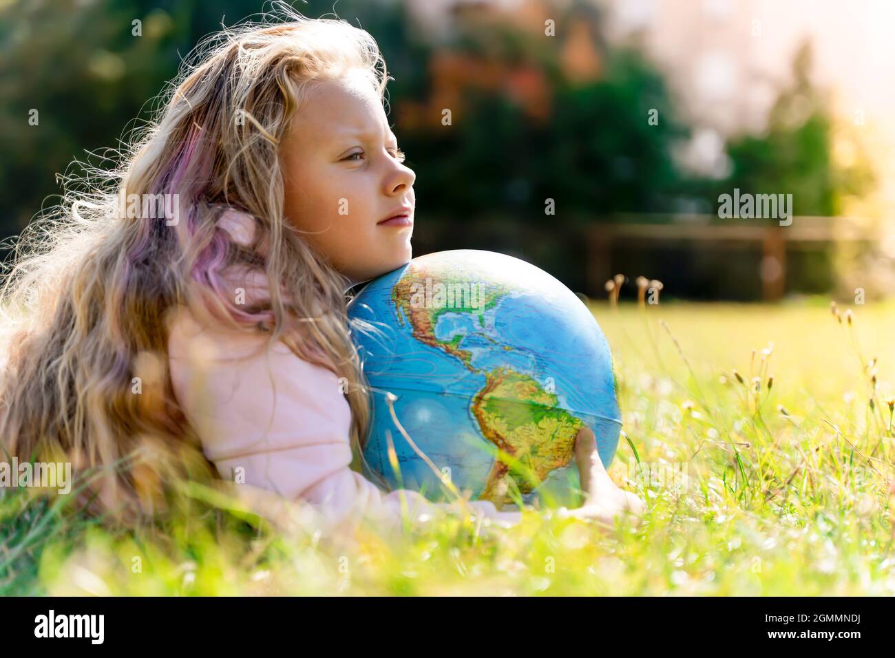 Kind mit Erdkugel. Porträt eines blonden europäischen Mädchens der Grundschule mit einem pädagogischen Globus des Planeten Erde in der Natur bei sonnigem Wetter. Konzept für Studium, Bildung, Naturschutz und Umweltschutz. Hochwertige Fotos Stockfoto