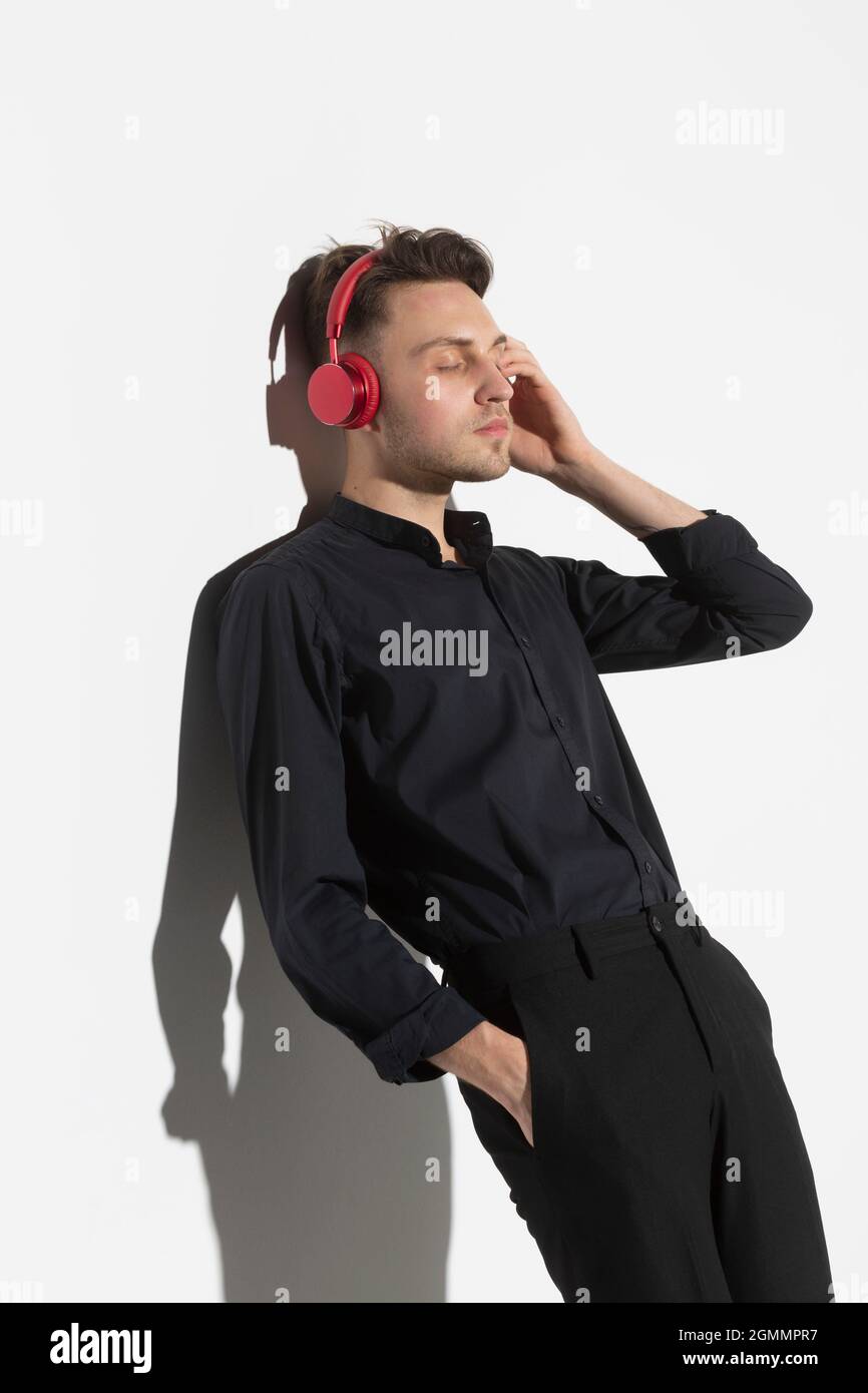 Gelassener junger Mann mit Kopfhörern, der Musik hört Stockfoto