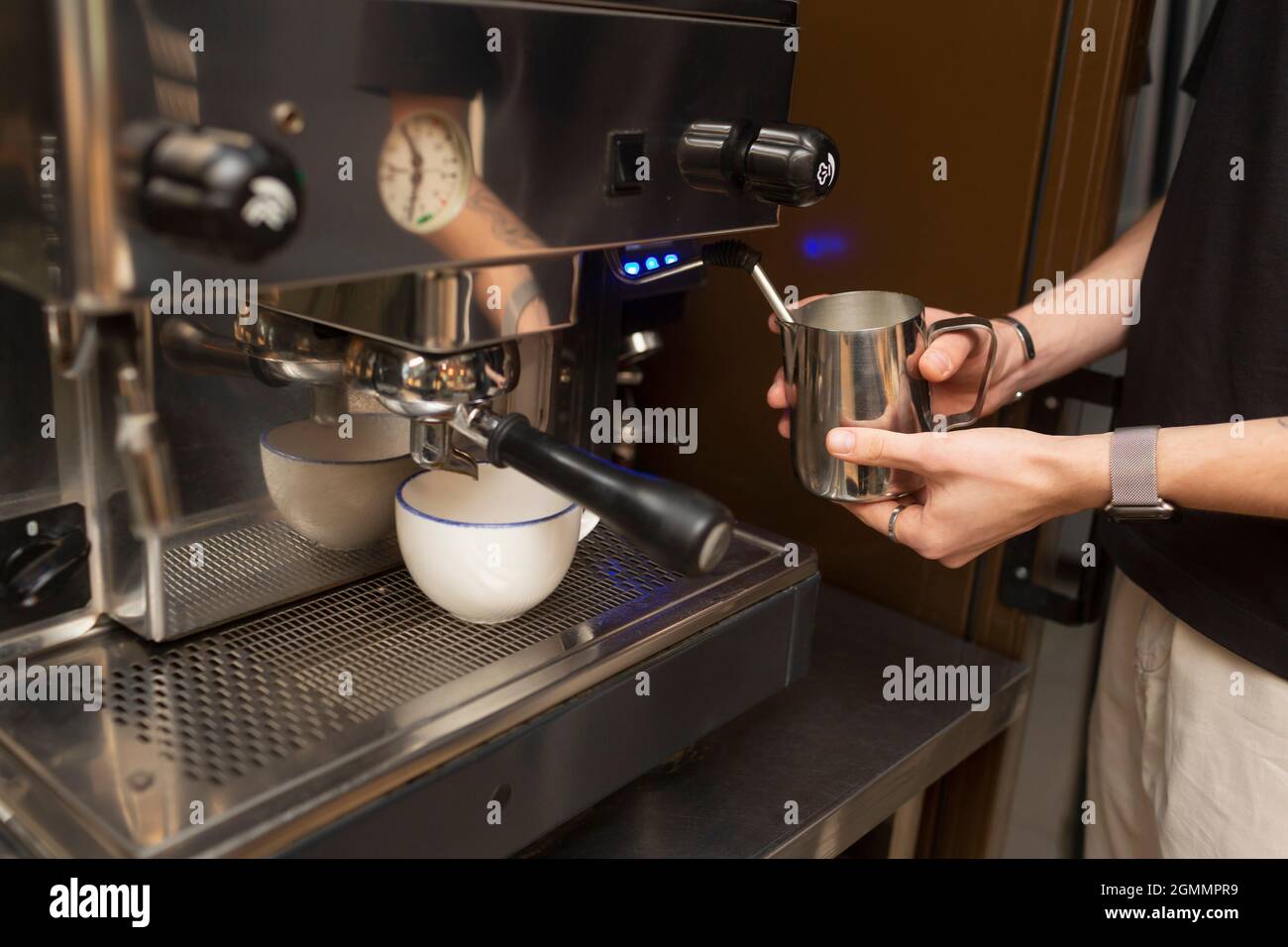 Barista dampfende Milch bei Espressomaschine in Cafe Stockfoto