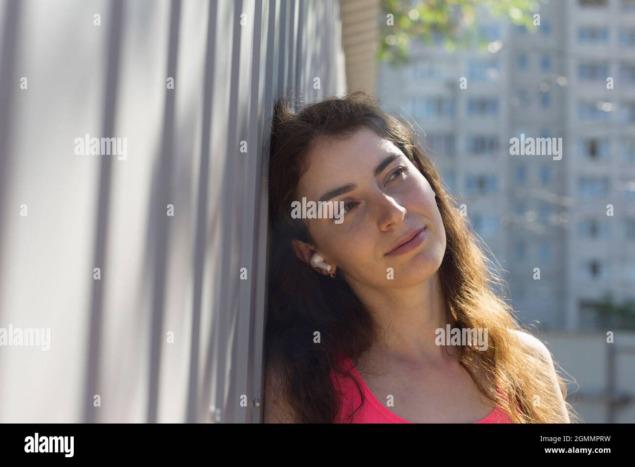 Ruhige junge Frau, die sich an der Wand lehnt Stockfoto
