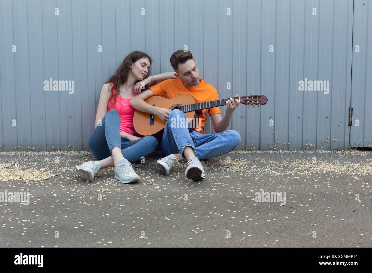 Junges Paar, das an der Wand Gitarre spielt Stockfoto