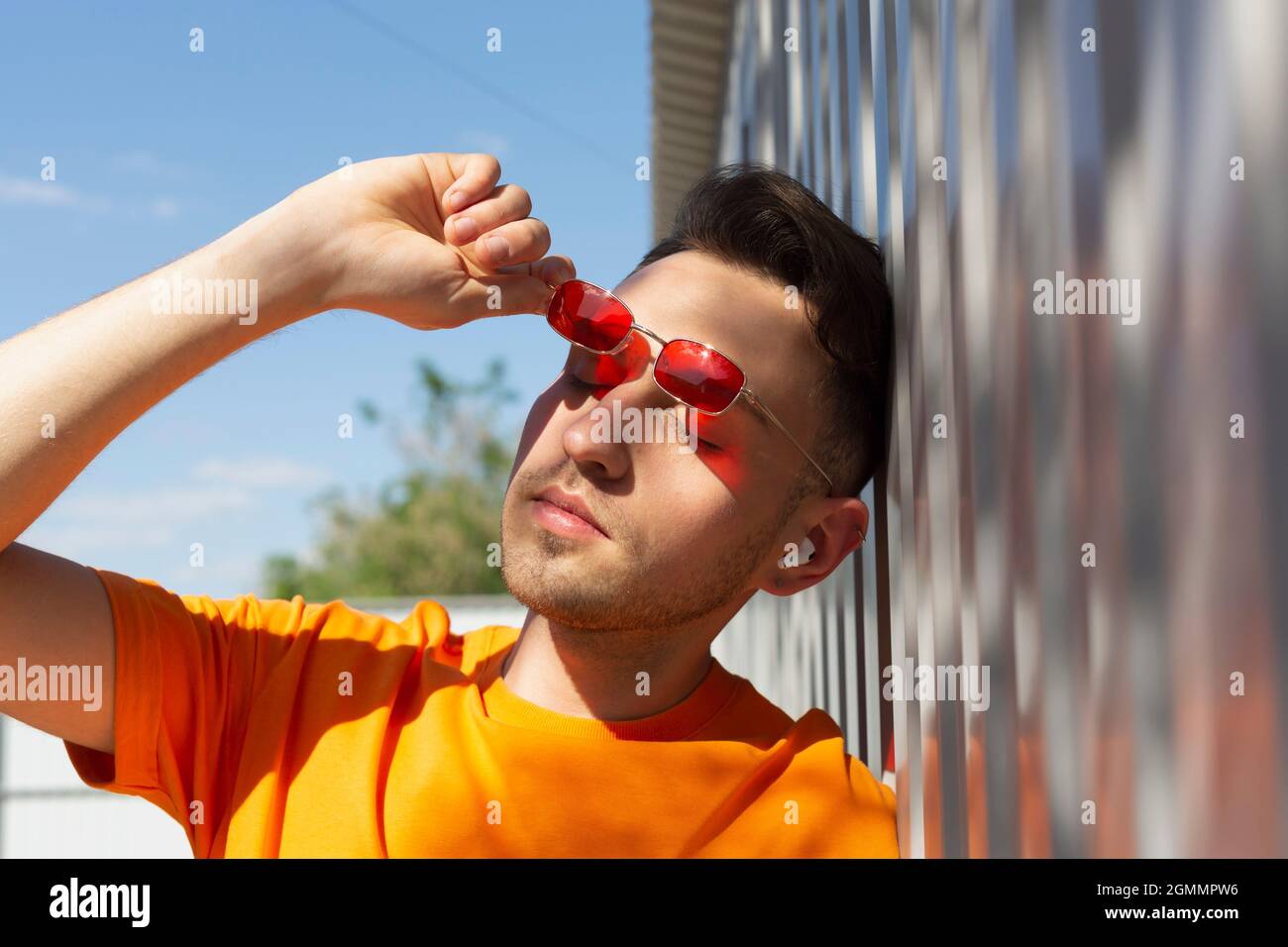 Gelassener junger Mann, der Sonnenbrillen entfernt Stockfoto