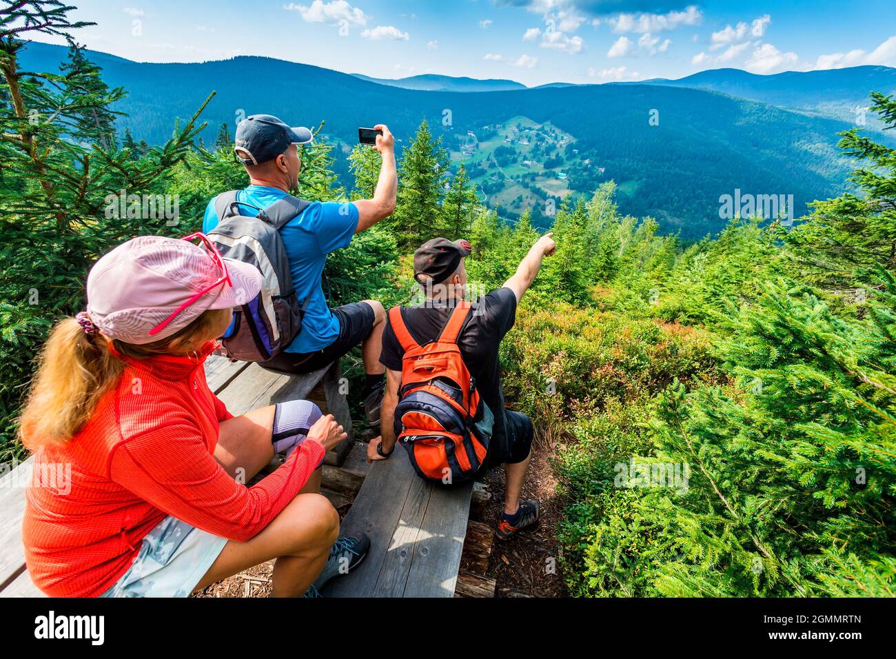 Drei Touristen sitzen und beobachten Sommer Bergpanorama Stockfoto