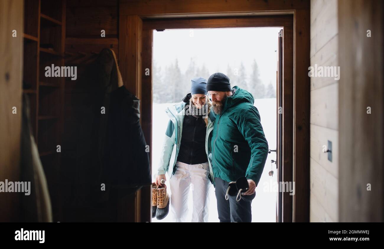 Reifes Paar betritt Holzhütte, Urlaub im Winter Natur Konzept. Stockfoto