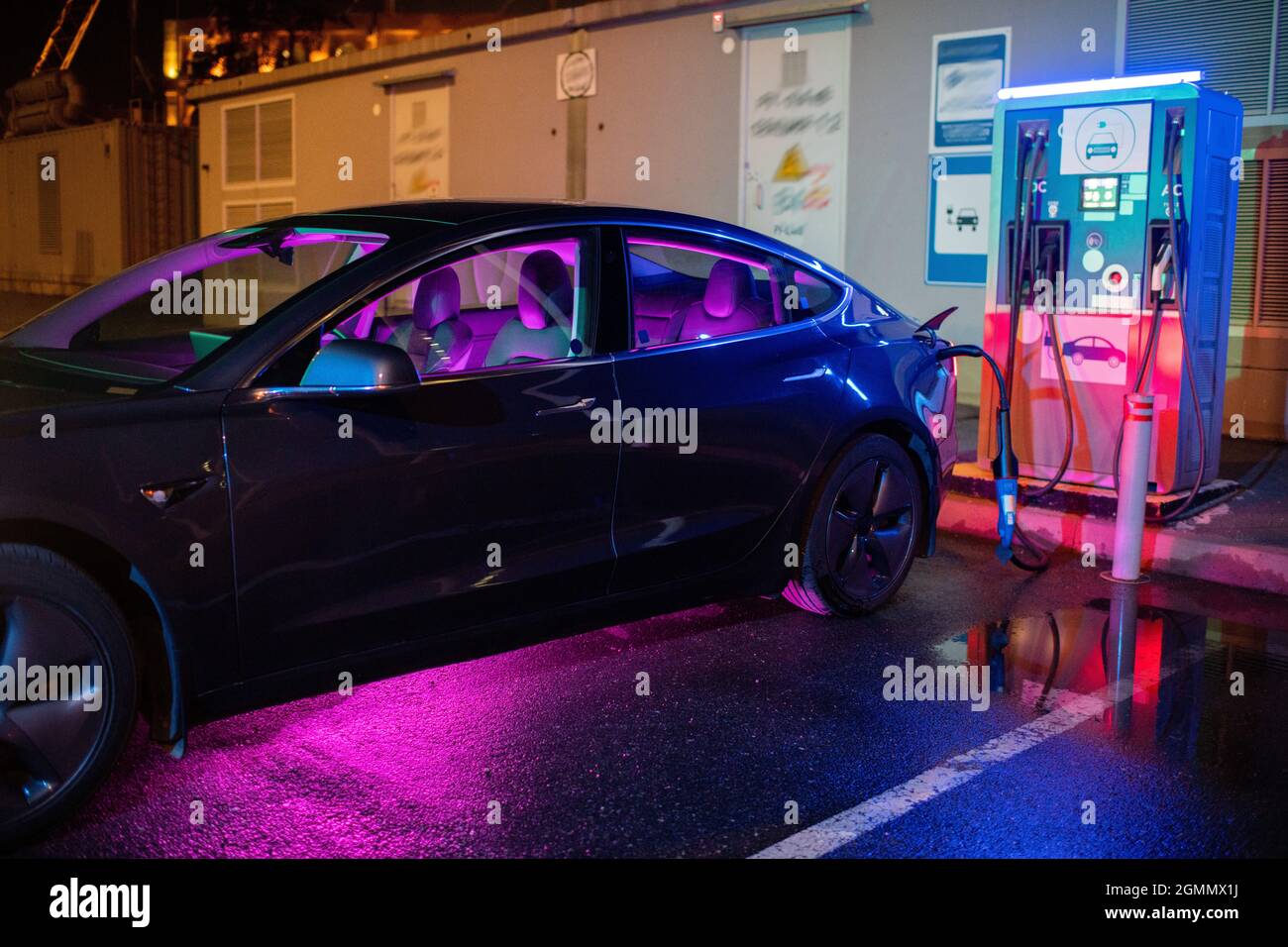 Schwarzes Elektroauto wird an der modernen EV-Ladestation geladen Stockfoto