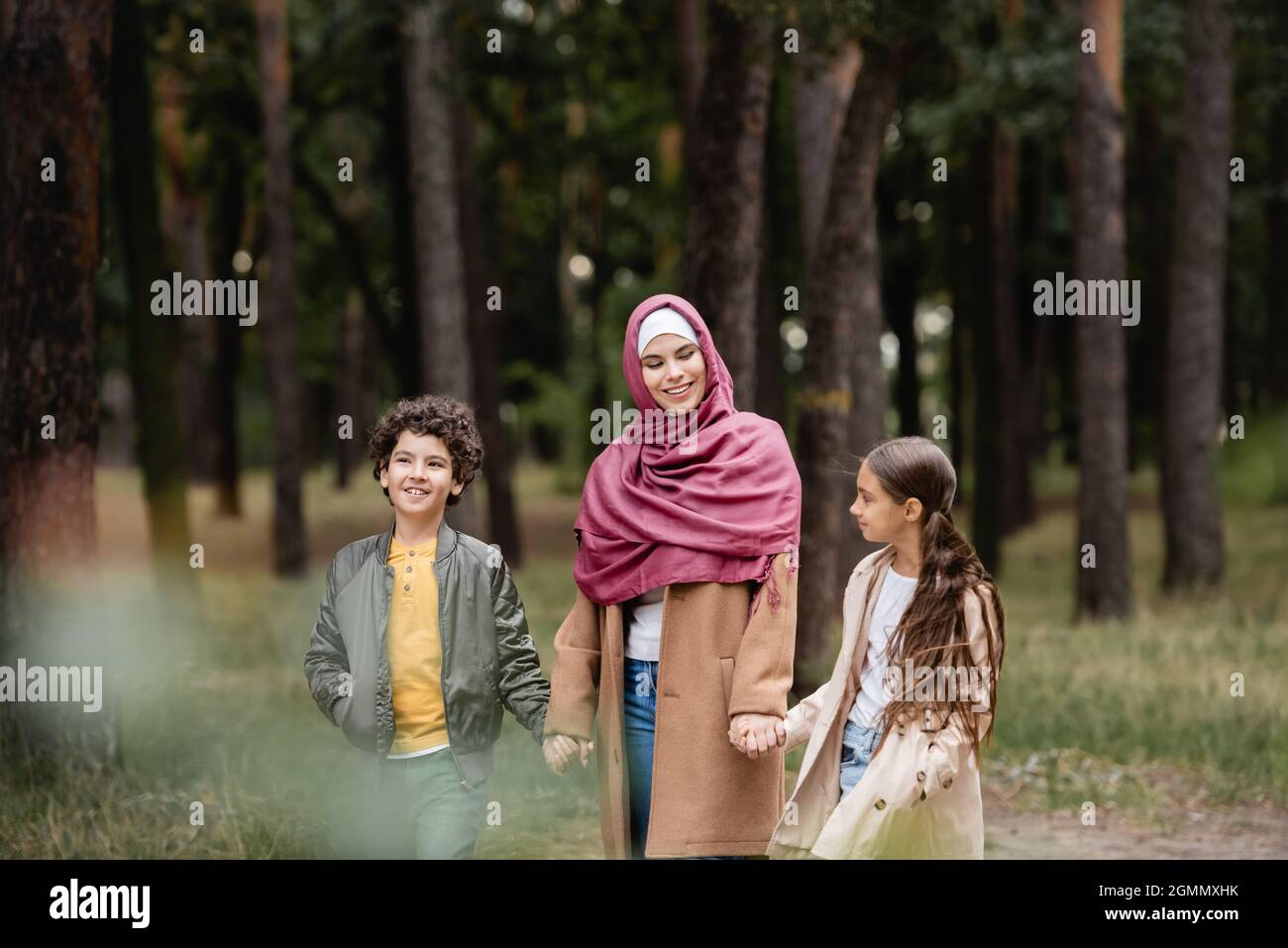 Muslimische Frau in Hijab hält die Hände von Kindern im Park Stockfoto