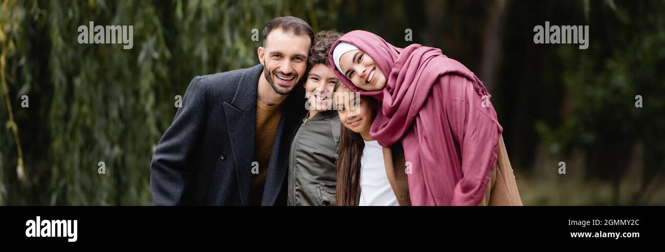 Arabische Familie mit Kindern, die im Park die Kamera anlächeln, Spruchband Stockfoto