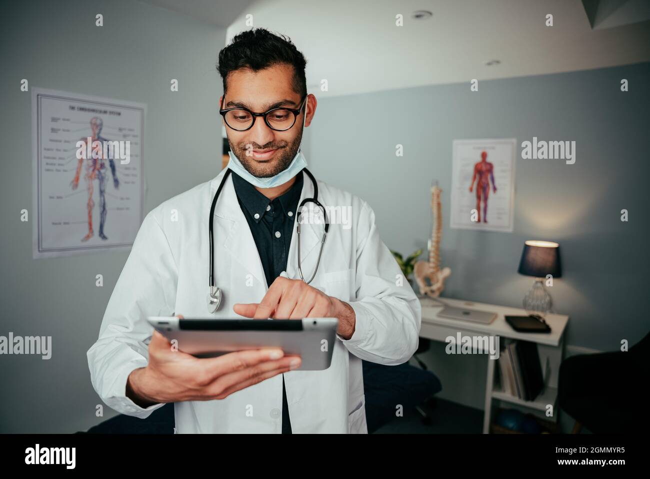 Gemischter Krankenschwester lächelnd mit OP-Ausrüstung stehend in der Klinik mit digitalem Tablet Stockfoto