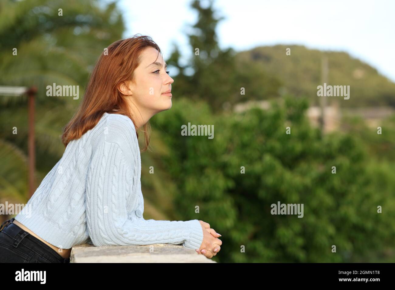 Seitenansicht Porträt einer Frau, die vom Balkon des Landhauses aus die Aussicht betrachtet Stockfoto