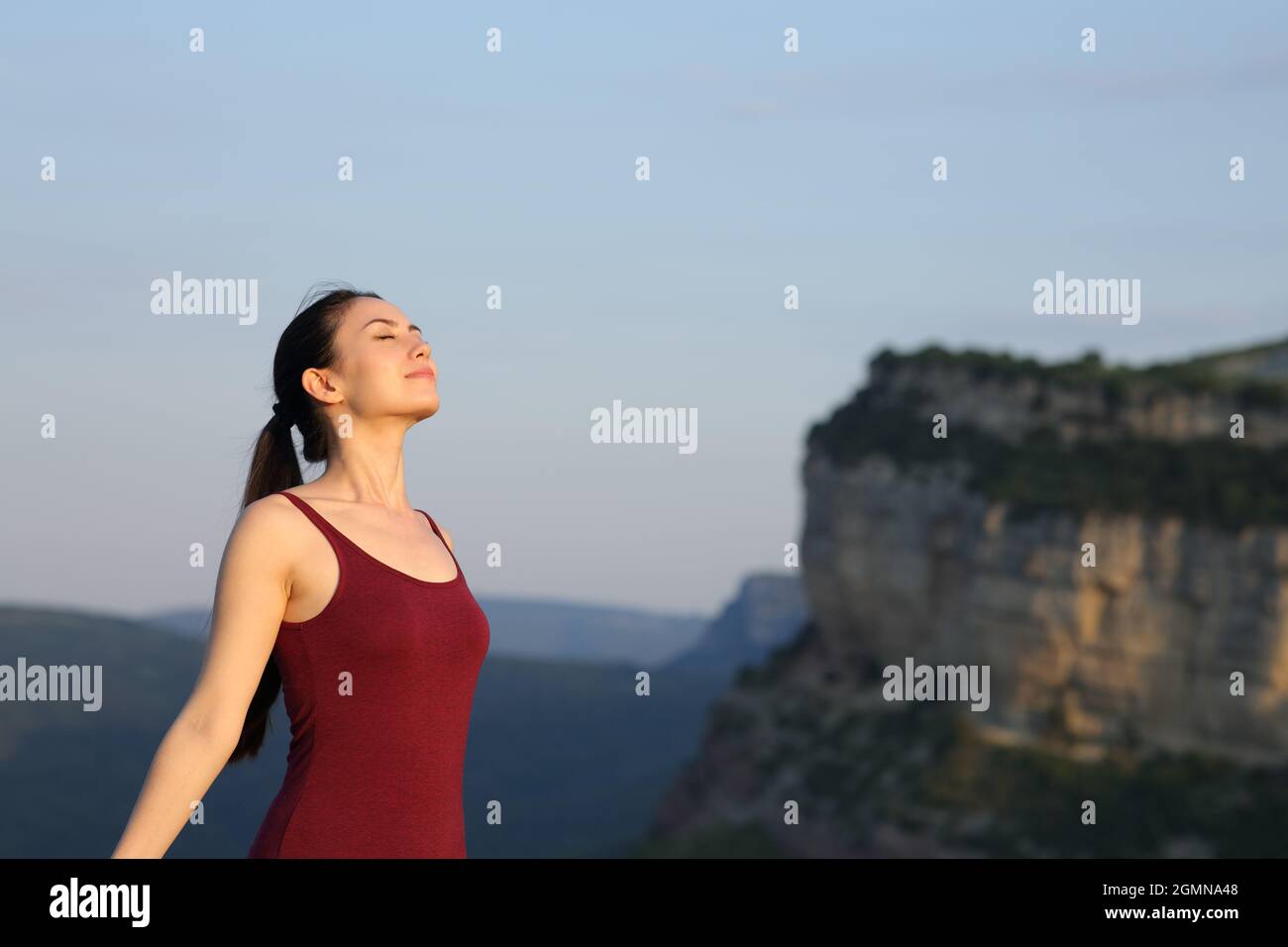 Sportlerin, die bei Sonnenuntergang frische Luft in den Bergen atmet Stockfoto