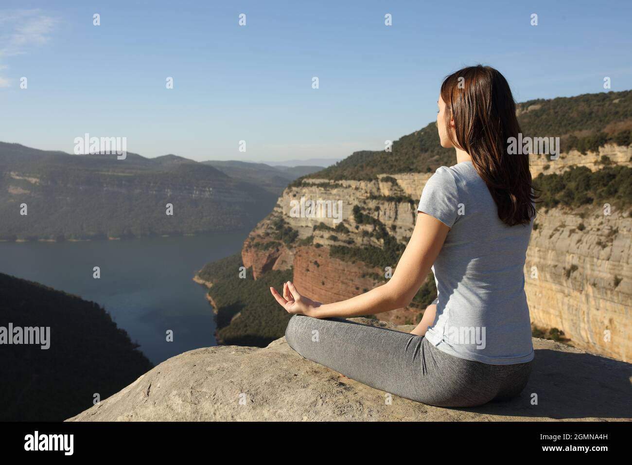 Frau, die Yoga-Lotus macht, posiert auf einer Klippe Stockfoto